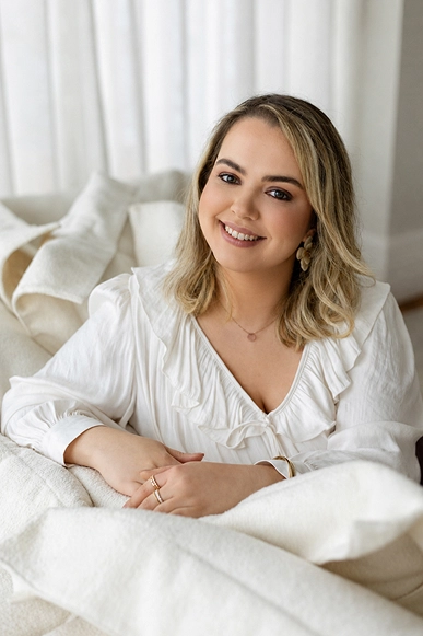 Foto da Ana Carolina de blusa branca e sorrinda